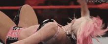 a woman with pink hair is wrestling in a ring .