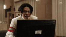 a man is sitting in front of a computer screen .
