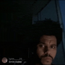 a man with a beard is looking at the camera in the dark .