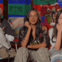 a woman is sitting in a chair with her hands on her chin .