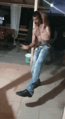 a shirtless man is dancing on a pole