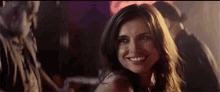 a woman is smiling and looking at the camera in a club .