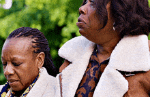 two women are standing next to each other and one is wearing a white fur coat