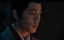 a close up of a man 's face with his eyes closed and a red collar .