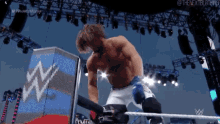 a wrestler is kneeling down in a wrestling ring while holding a rope .