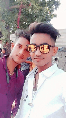 two young men are posing for a picture and one of them is wearing sunglasses