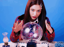 a woman in a plaid jacket is sitting at a table looking at a glass ball