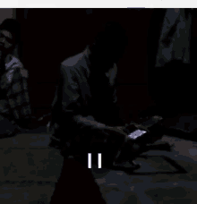 a man is sitting on the floor with a cell phone in his hand and the number 11 is visible