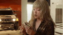 a woman in a leopard print jumpsuit is eating a sandwich in front of a hummer