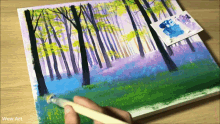 a person is painting a forest with a brush on a canvas .