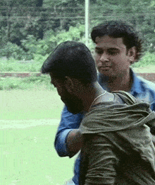 two men are standing next to each other in a grassy field .
