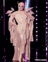 a drag queen in a white dress with birds on her arms