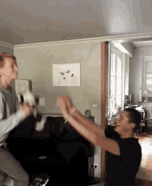 two men are jumping in the air in a living room with a painting on the wall behind them