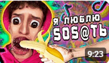a man is eating a banana with his mouth open and a hand holding it .