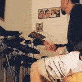 a man is playing a drum set in a room with a picture on the wall that says ' twice '