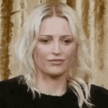 a close up of a woman 's face with blonde hair wearing a black shirt .