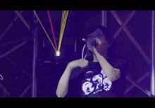 a woman singing into a microphone in front of a purple background