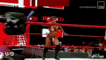 a woman is standing in a wrestling ring while a man is laying on the ground .