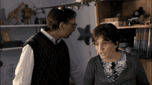 a man and a woman are standing next to each other in front of a shelf with a star on it