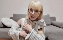 a woman wearing glasses and a white sweater is holding a star shaped item