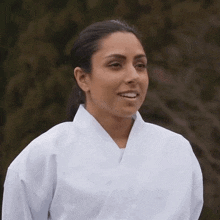 a woman wearing a white karate uniform smiles for the camera