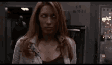 a woman with red hair and white eyes is standing in front of a machine that says 7711