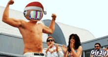 a shirtless man wearing a santa hat flexes his muscles in front of a crowd