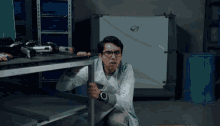 a man wearing glasses and a watch is looking under a shelf