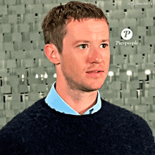 a man wearing a blue shirt and a black sweater with purepeople written on the bottom right