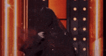 a close up of a person standing in front of a wall with lights .