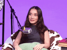 a woman sits in a bean bag chair with a microphone behind her