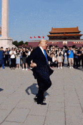 a man in a suit is dancing in front of a building that says ' chinese ' on it