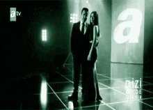 a man and a woman are standing next to each other on a stage in a dark room .