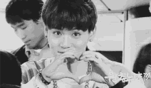 a young boy making a heart shape with his hands .