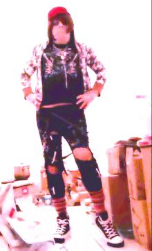 a person wearing ripped jeans and converse shoes stands in front of a stack of boxes