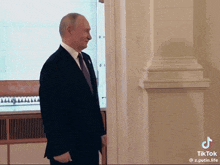 a man in a suit and tie is standing in a hallway next to a door .