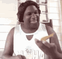 a man wearing a wig and a white tank top is holding a piece of food in his hand .