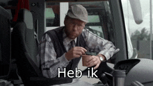 a man in a plaid shirt is sitting in a car with heb ik written below him