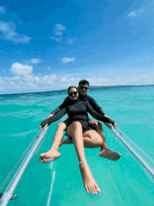 a man and a woman are sitting on a clear raft in the ocean