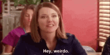 a woman is sitting at a table and saying `` hey , weird . ''