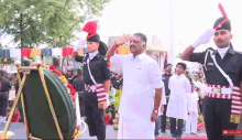 a man in a white shirt salutes in front of soldiers in uniform