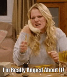 a woman is sitting at a table talking on a phone and says i 'm really amped about it