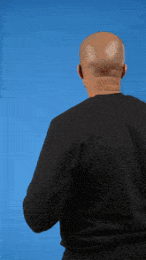 the back of a man wearing a black sweater with a blue background