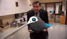 a man in a suit and tie is holding a bird with a blue beak .