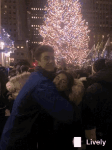 a couple hugging in front of a christmas tree with the word lively on the bottom