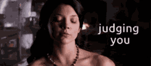 a naked woman with her eyes closed and the words judging you behind her .