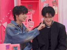 two young men are standing next to each other in front of a pink locker with a heart on it