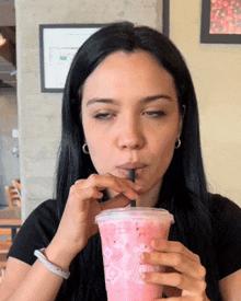 a woman drinking a pink drink with a straw