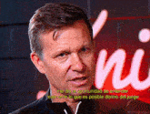 a man is talking in front of a sign that says " ni "