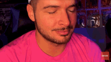a man wearing a pink shirt has his eyes closed in front of a wall of x-men action figures